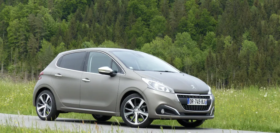 Manuel d'utilisation Peugeot 208 en PDF ouvert sur un smartphone posé sur le tableau de bord